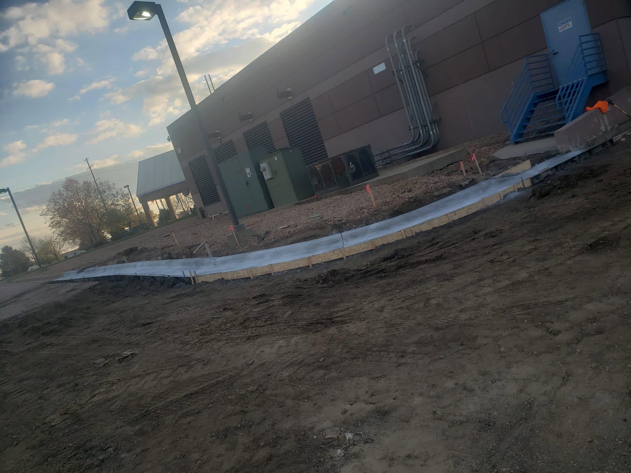 A long curved freshly poured concrete sidewalk and curb running along a commercial building
