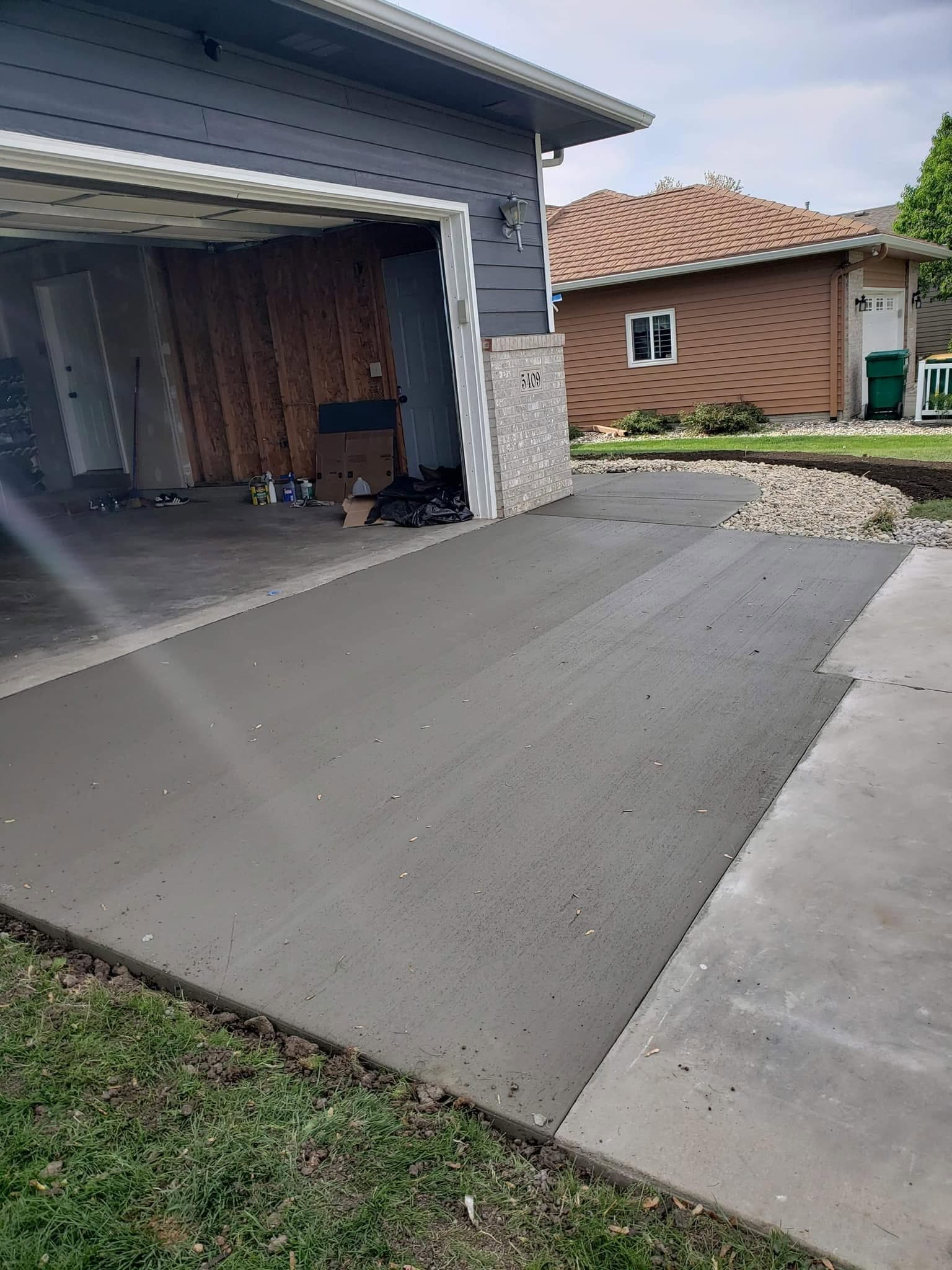 A wide fresh broom-finished concrete driveway leading to the open garage of a new home