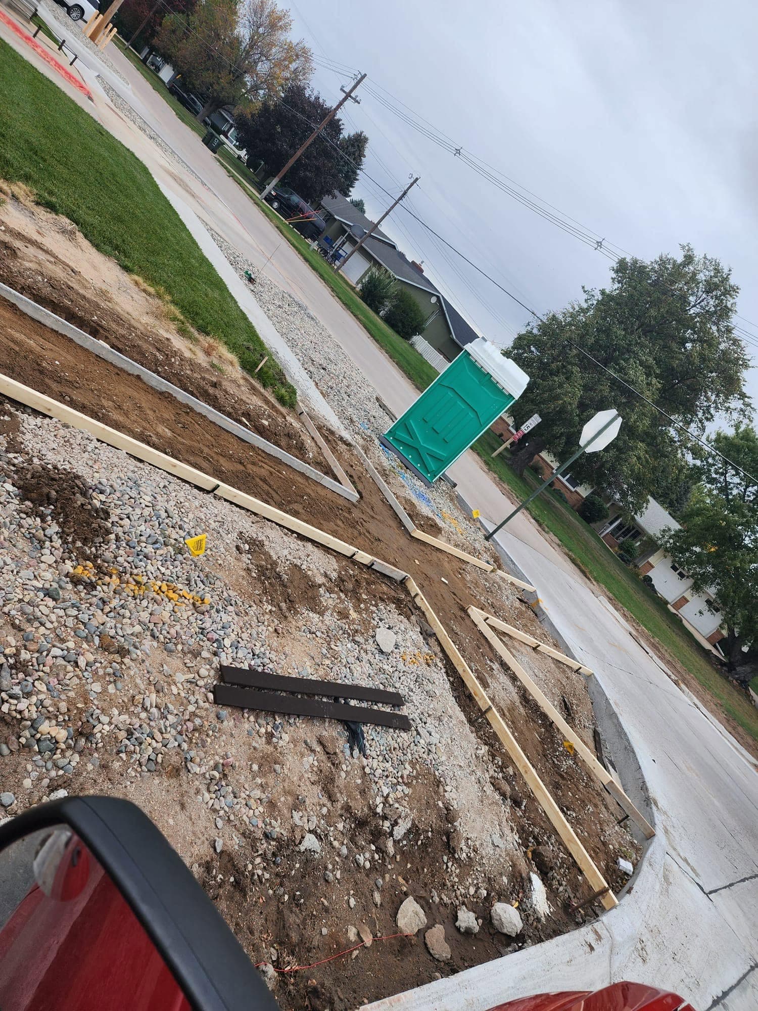 Wood form boards staked out on a gravel base at a street corner before the pour
