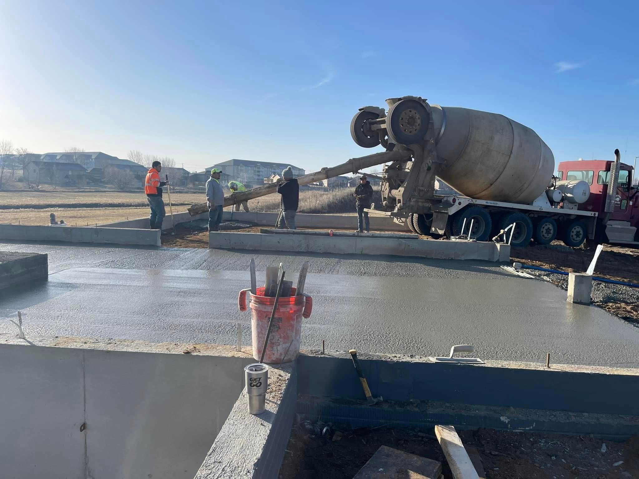A ready-mix truck placing concrete off its chute as the crew works a fresh slab